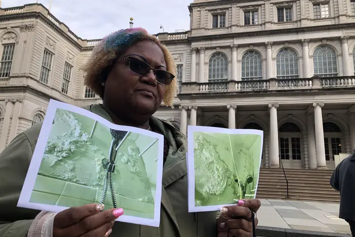 Saundrea I. Coleman holds up two pictures of her moldy bathroom taken a year apart. NYCHA still hasn't come to fix the ongoing issue.